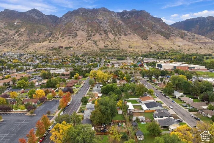 Aerial perspective featuring extensive mountain range backdrop, mature deciduous trees, and established neighborhood street infrastructure