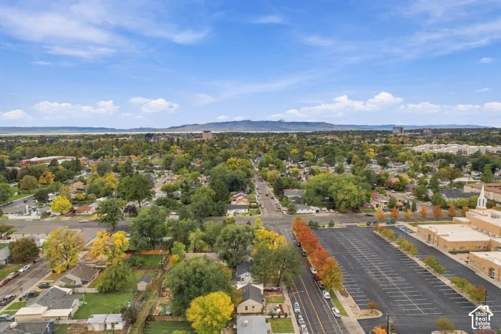 Aerial perspective of a neighborhood setting featuring mature deciduous trees and prominent mountain backdrops