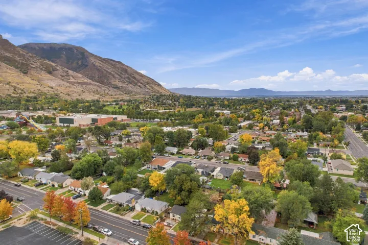 Aerial perspective featuring an expansive mountain backdrop, mature trees, and established street-level infrastructure