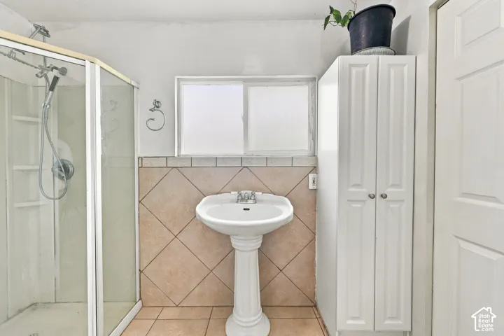 Pedestal sink, tiled shower enclosure with sliding glass door, and built-in floor-to-ceiling storage cabinetry