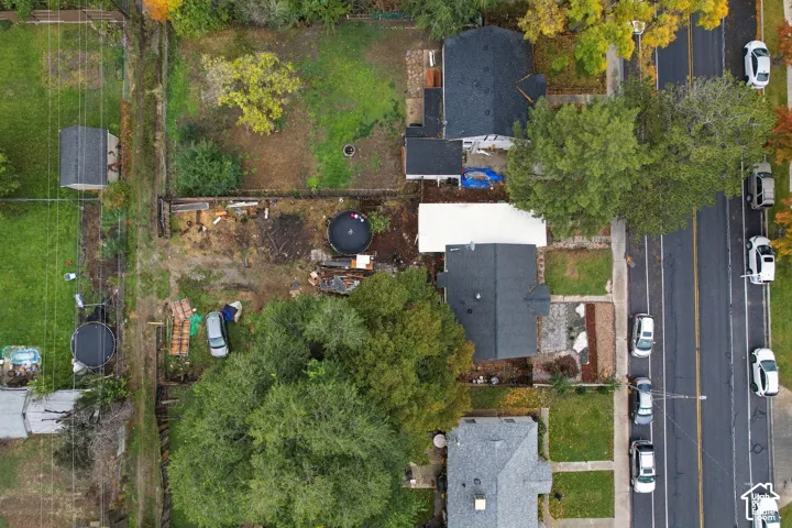 Aerial view of property featuring a detached storage shed, fenced perimeter, and mature trees