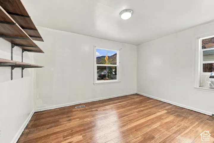 Interior room featuring wood-finish flooring, dual windows with exterior mountain scenery, and wall-mounted wooden shelving with metal brackets