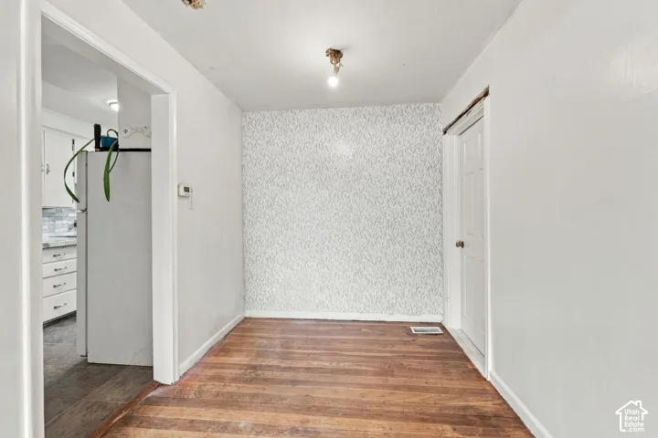 Interior space featuring wood-finish flooring, a textured accent wall, a six-panel door, and a ceiling-mounted light fixture