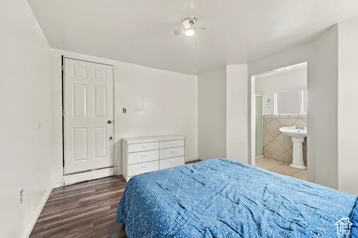 Wood-finish flooring, white panel door, ceiling-mounted light fixture, pedestal sink, and tile wainscoting