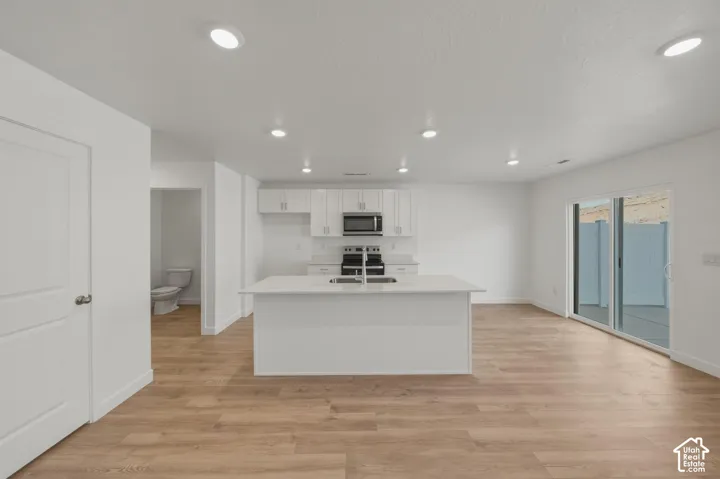 Open-concept living area with wood-finish flooring, recessed lighting, and a white kitchen island