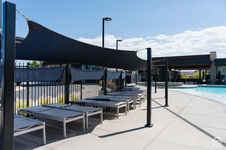 Poolside lounge area featuring multiple shaded seating structures, a paved deck, and a water feature
