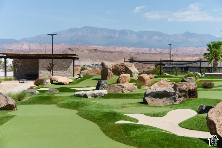 Putting green with artificial turf, sand traps, and large natural rock landscaping