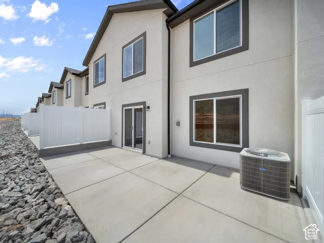 Private concrete patio with sliding glass door access, bordered by a white privacy fence and rock landscaping