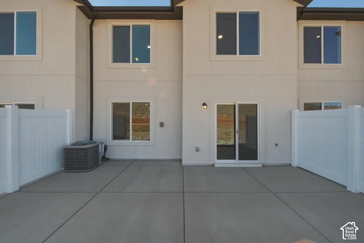 Private patio with concrete surfacing, white vinyl fencing, and a sliding glass door entry