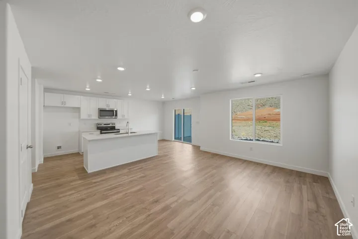 Open concept living area featuring wood-finish flooring, recessed lighting, and a kitchen island with a sink