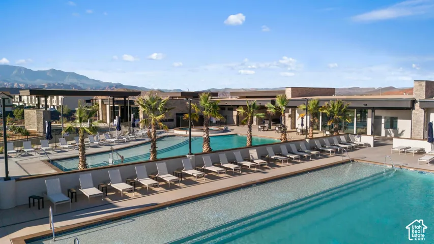 Expansive pool area featuring multiple swimming pools, a surrounding concrete deck, and mature palm trees