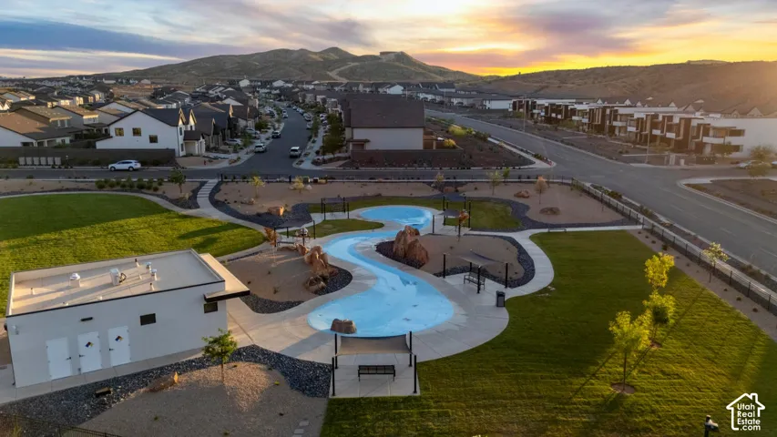 Community park featuring a splash pad, green spaces, paved pathways, and shaded seating areas