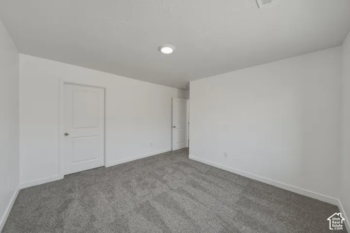 Neutral white walls, recessed ceiling lighting, and gray carpeting