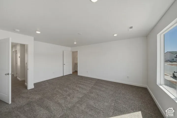 Recessed lighting, white walls, gray carpeting, white trim, and a large window