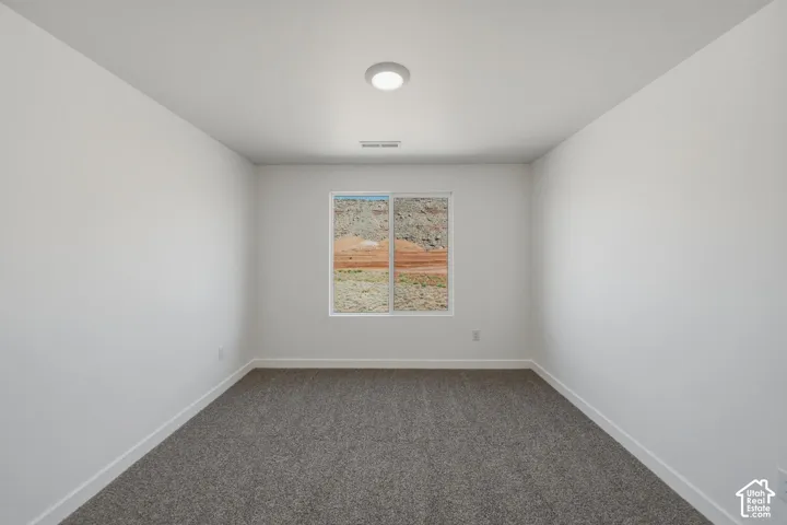 White walls featuring a single window, gray carpet, and overhead lighting