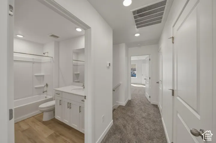 Bathroom with a white vanity, integrated sink, and wood-finish flooring