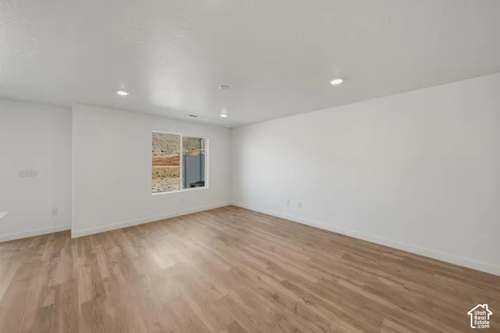 Wood-finish flooring, white walls, recessed lighting, and a multi-pane window