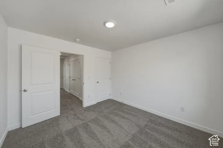 Neutral wall paint, gray carpet flooring, recessed ceiling light, white interior doors, and door hardware