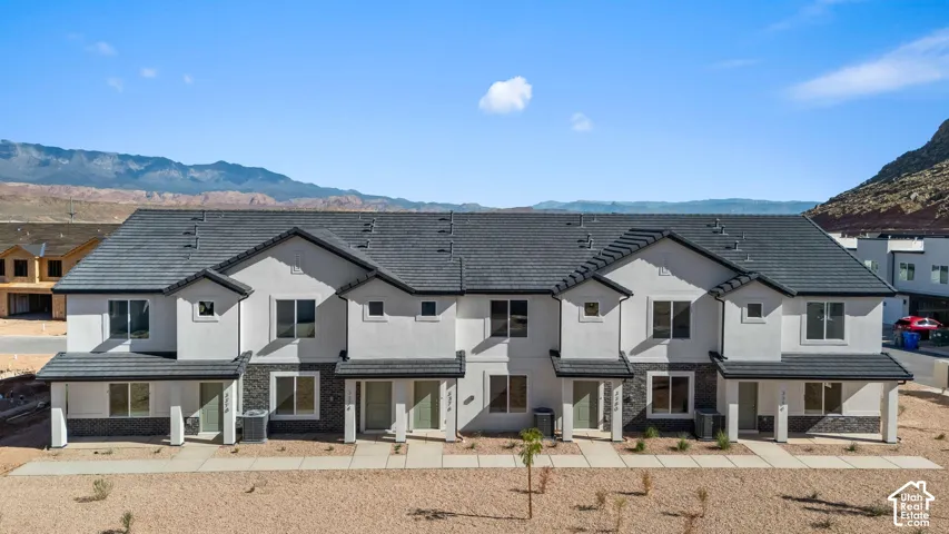Modern townhome exteriors featuring white stucco, dark stone accents, and covered entryways