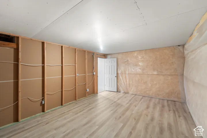 Unfinished interior space featuring wood-finish flooring, a paneled door, and exposed framing