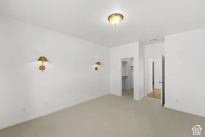 Neutral tone wall paint, flush mount ceiling light, wall sconce lighting, built-in closet shelving, and light tone carpeting