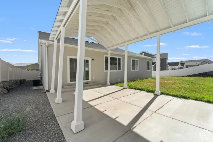 Attached covered patio with concrete flooring, gravel landscaping, and a fenced perimeter