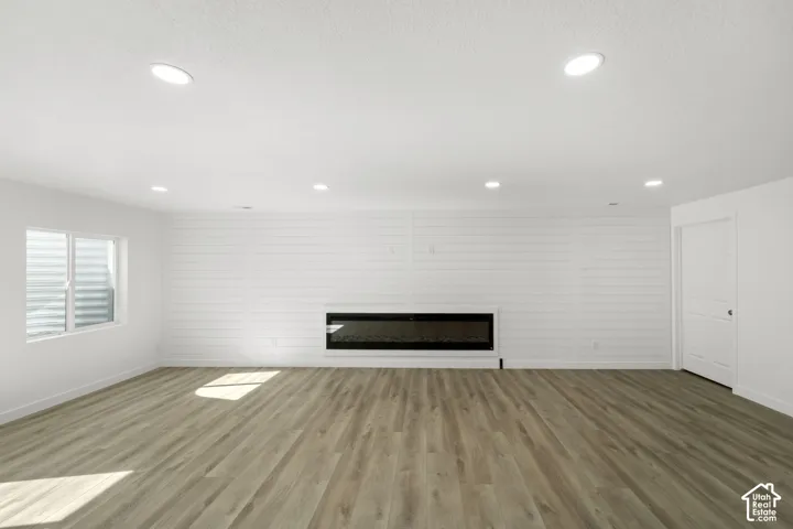 Expansive room featuring wood-finish flooring and recessed lighting