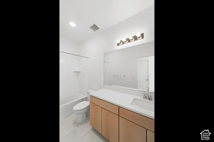 Bathroom featuring a single vanity with wood-finish cabinetry, a large mirror, and overhead vanity lighting