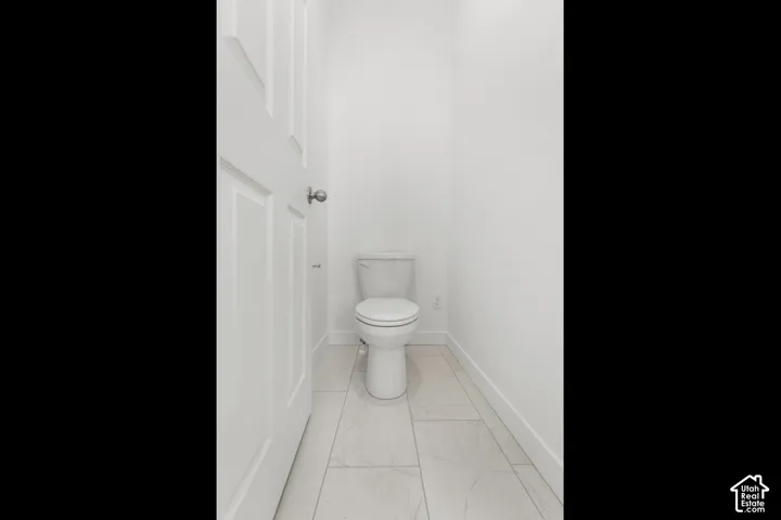 White paneled door, white walls, and light-toned tile flooring