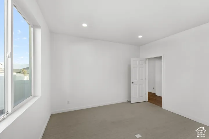 Recessed lighting, white walls, and neutral carpet flooring