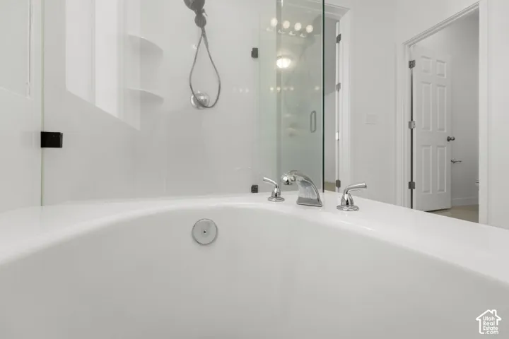 Built-in bathtub with polished chrome fixtures and an integrated shower system, featuring a clear glass enclosure