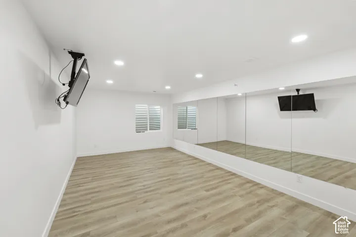 Expansive room featuring wood-finish flooring, recessed lighting, and a wall-mounted mirror