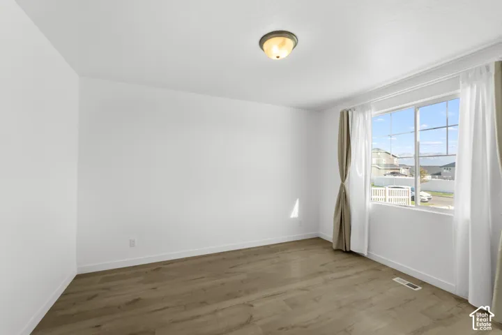 Wood-finish flooring with white baseboards and neutral wall paint