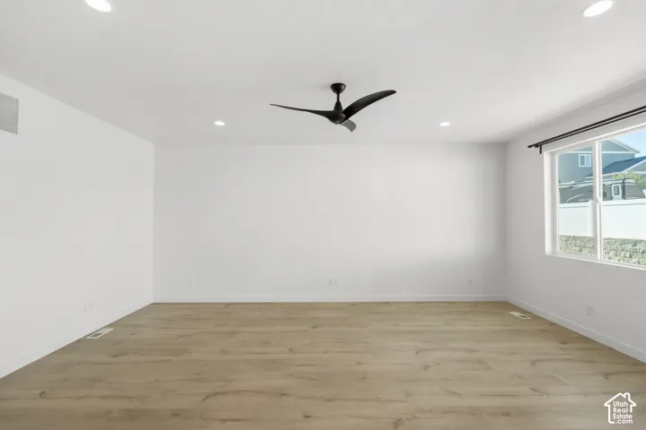 Wood-finish flooring with recessed lighting, a modern ceiling fan, and a large window