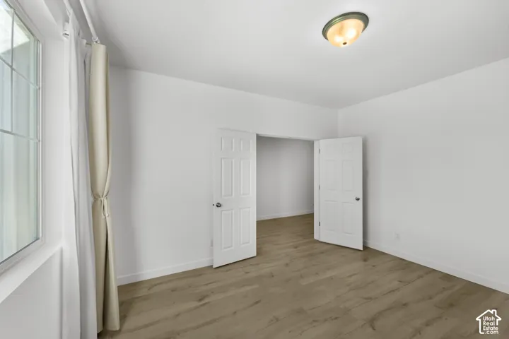 Wood-finish flooring, white paneled interior doors, and a flush mount ceiling light fixture
