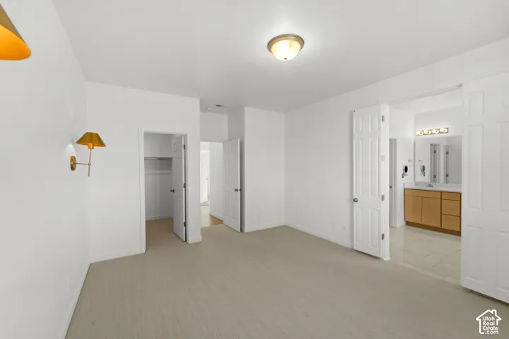 Neutral-toned carpet flooring, white walls, ceiling-mounted light fixture, wall-mounted sconce, and white paneled doors