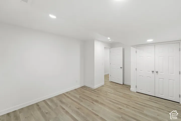 Recessed lighting, wood-finish flooring, white walls, white paneled doors, and a double-door closet