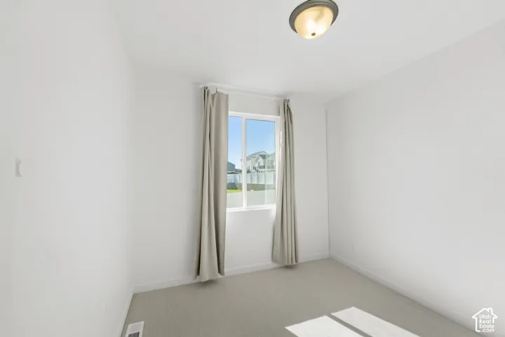 Carpeted room with a single window and an overhead light fixture
