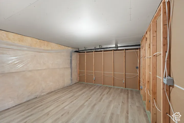 Expansive unfinished space featuring wood-finish flooring, exposed framing, and installed electrical wiring