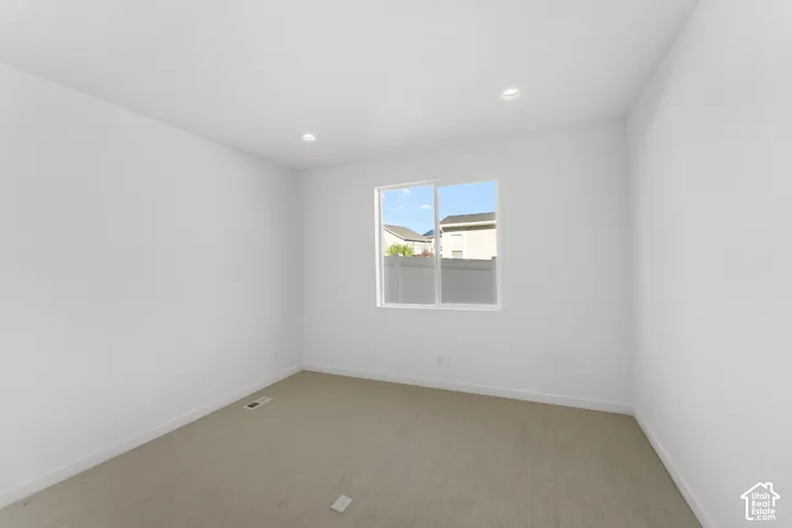Recessed ceiling lighting, white walls, carpeted flooring, and a double-pane window