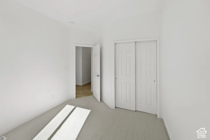 Light-colored carpeting, white walls, and white sliding closet doors