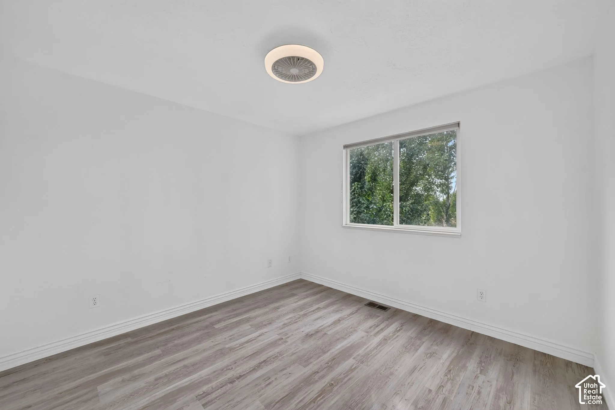 Neutral white walls, wood-finish flooring, and a ceiling-mounted light fixture
