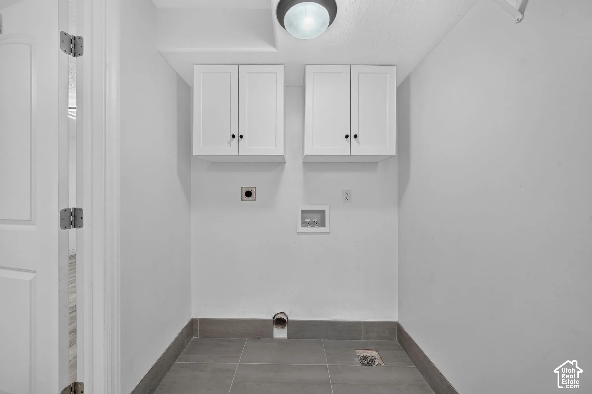 White shaker-style cabinetry with dark hardware, a surface-mount ceiling light, and gray tile flooring with a matching baseboard