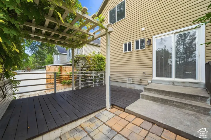 Ground-level patio with paver stone flooring, wood-finish deck, and concrete steps