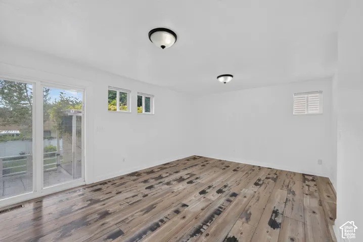 Wood-finish flooring with a distressed pattern, white walls, and a sliding glass door