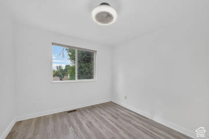 Bright interior with a window featuring exterior scenery, wood-finish flooring, and a ceiling-mounted light fixture