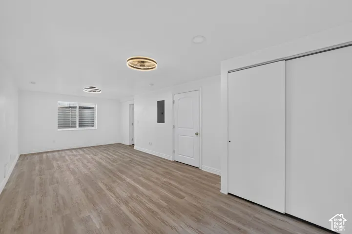 Spacious room featuring wood-finish flooring, white walls, and a window with blinds