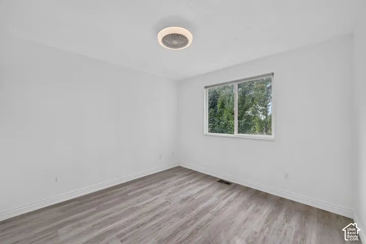 Neutral white walls, wood-finish flooring, and a ceiling-mounted light fixture