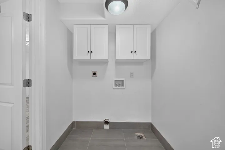 White shaker-style cabinetry with dark hardware, a surface-mount ceiling light, and gray tile flooring with a matching baseboard