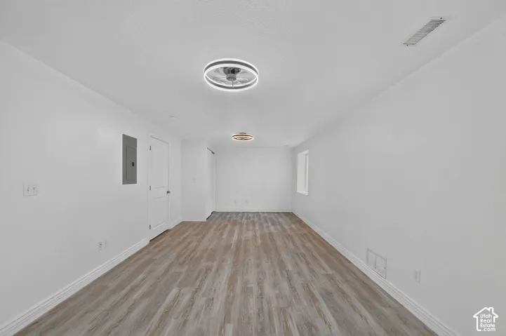 Spacious room featuring wood-finish flooring, white walls, and contemporary ceiling light fixtures
